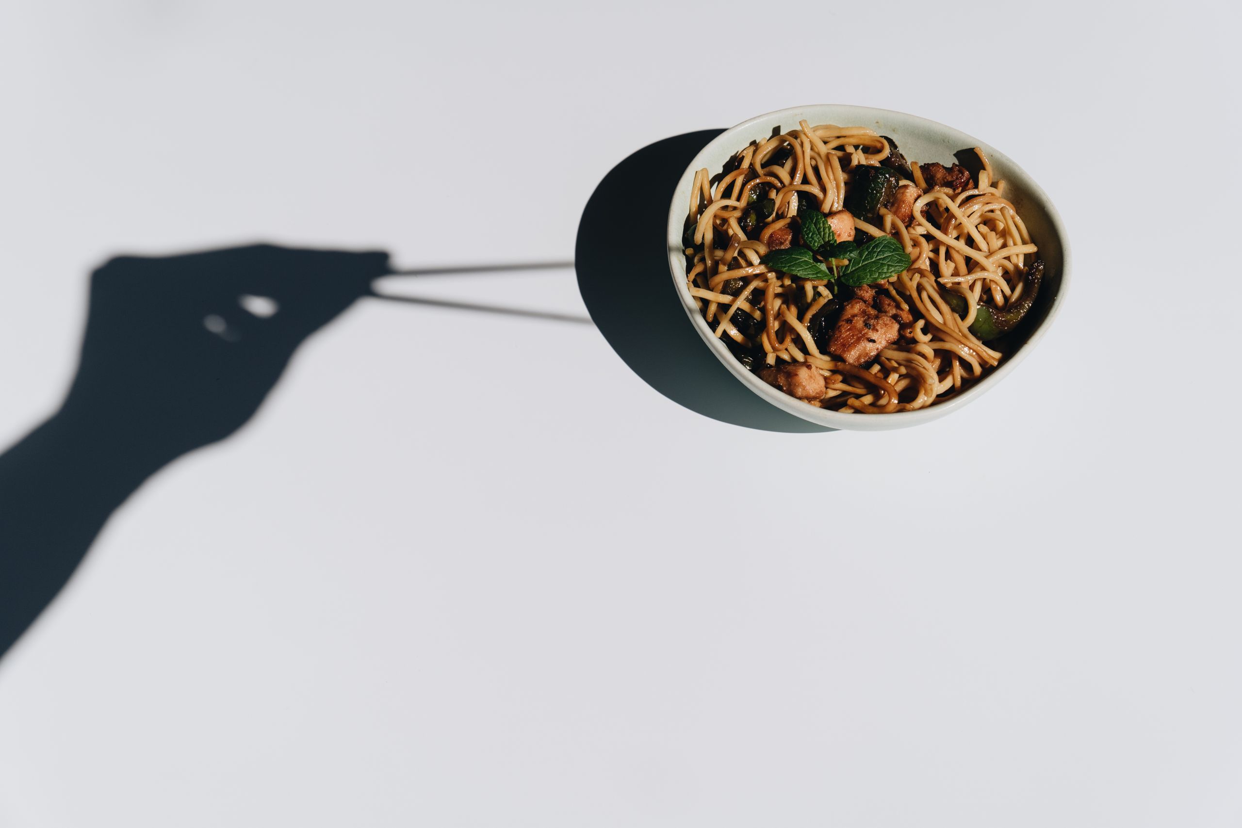 Creative image of a noodle bowl with artistic shadow play and minimalistic composition.