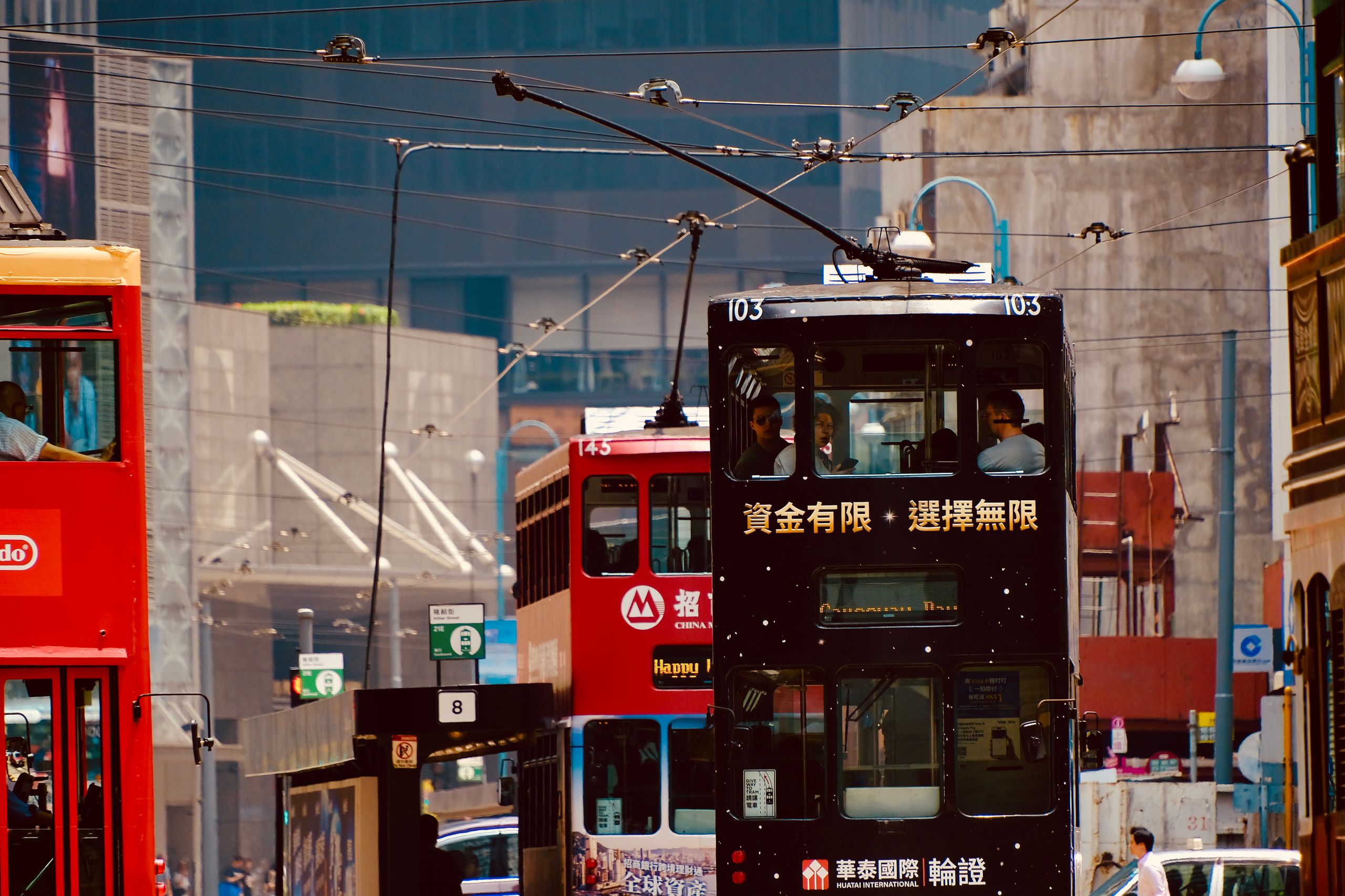 Double-decker trams in lively Hong Kong street, showcasing urban transport.